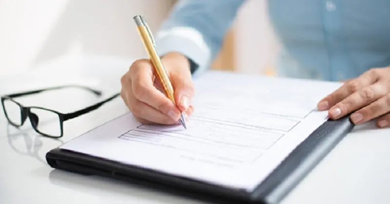 Hình ảnh một người đang rà soát và kiểm tra lại sơ yếu lý lịch cẩn thận bằng bút trước khi nộp