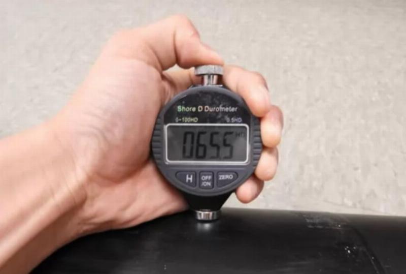 Hình ảnh một máy đo độ cứng Shore (Durometer) cầm tay đang đo trên một miếng cao su