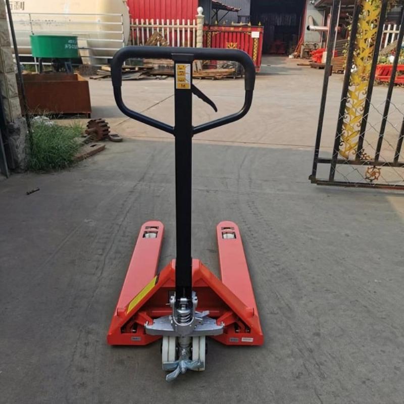 Một nhân viên đang kiểm tra càng nâng của chiếc xe nâng tay inox màu trắng trong một nhà máy