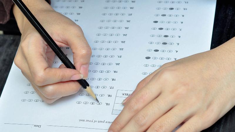 Một phụ huynh đang cẩn thận điền thông tin vào mẫu đơn xin nhập học lớp 1 trên bàn làm việc tại nhà