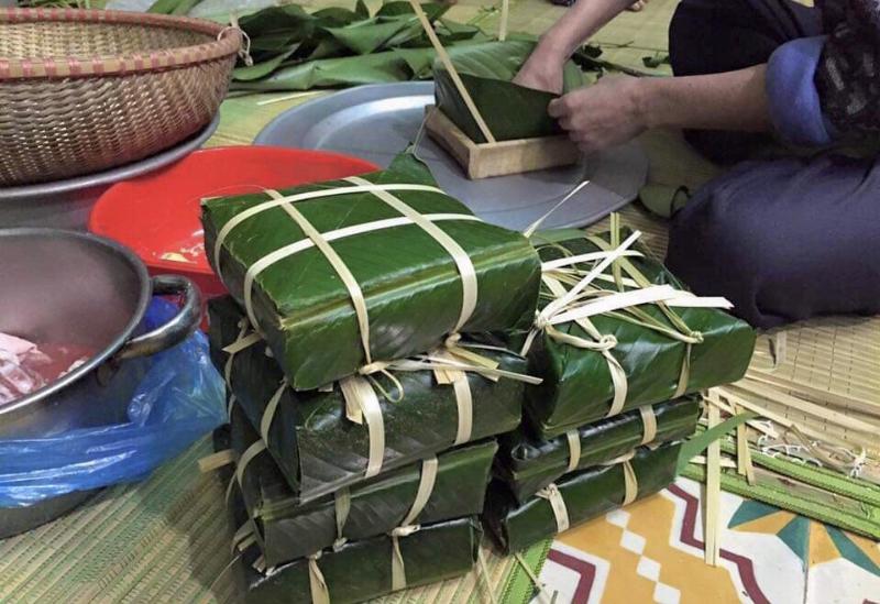 Hình ảnh không khí Tết Nguyên Đán với gia đình quây quần bên cây mai/đào, bánh chưng, mâm ngũ quả, thể hiện không khí sum họp